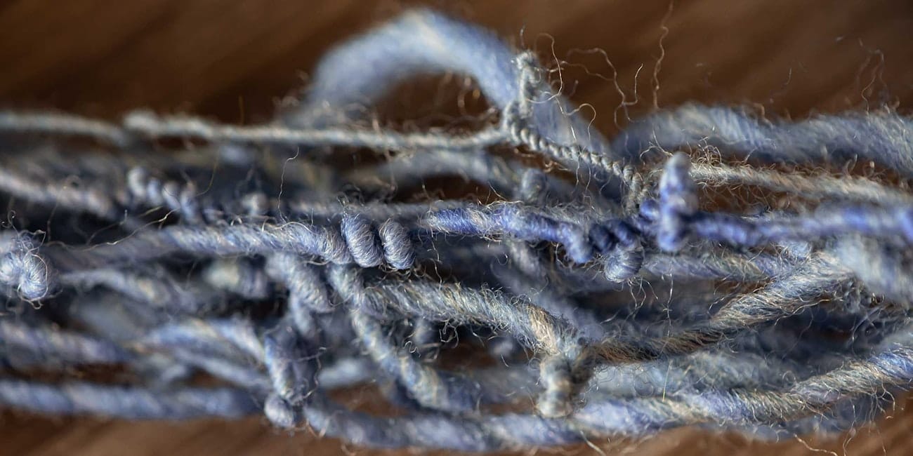 A highly twisted blue singles yarn rests on a brown background.