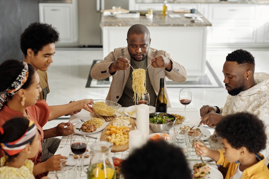 Free A warm family gathering enjoying dinner together with wine and pasta. Stock Photo